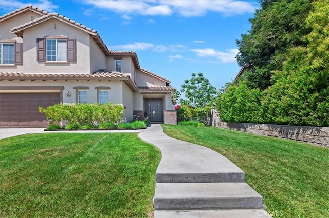 mediterranean / spanish home with an attached garage, stucco siding, a front yard, a tiled roof, and driveway