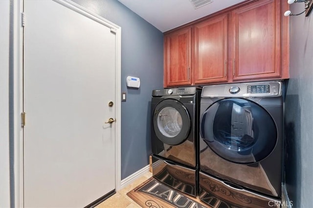 washroom with baseboards, visible vents, cabinet space, and washer and clothes dryer