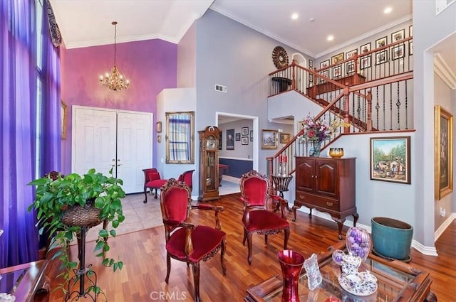 sitting room featuring wood finished floors, baseboards, a chandelier, a high ceiling, and stairs