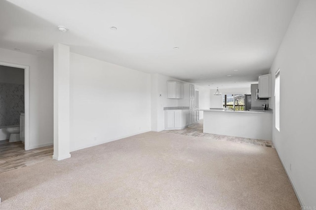 unfurnished living room featuring baseboards and light carpet