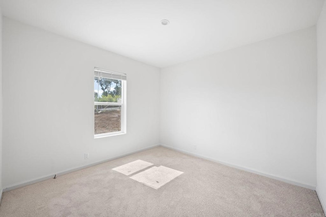 spare room featuring baseboards and light carpet