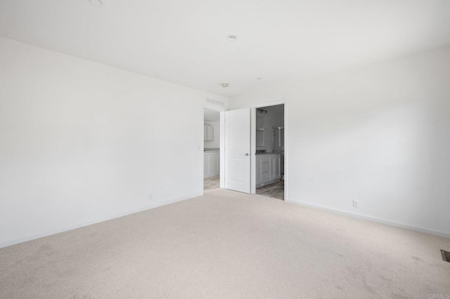 spare room with baseboards, visible vents, and light carpet