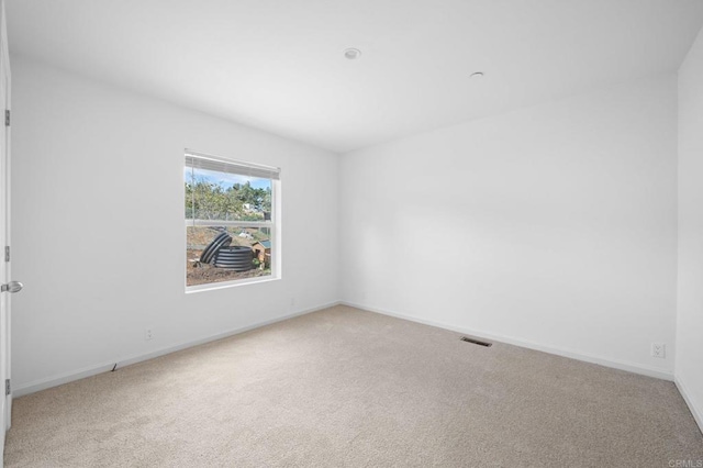 unfurnished room featuring baseboards, visible vents, and light colored carpet