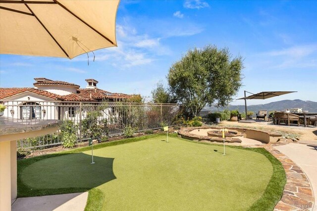 view of home's community featuring fence, a fire pit, a mountain view, and a patio area