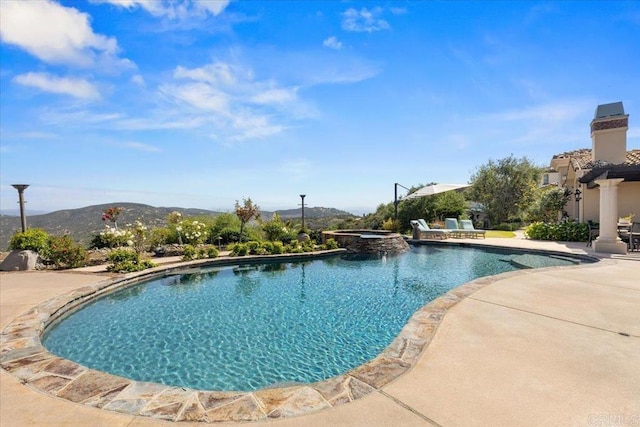 view of pool with a patio, a pool with connected hot tub, and a mountain view