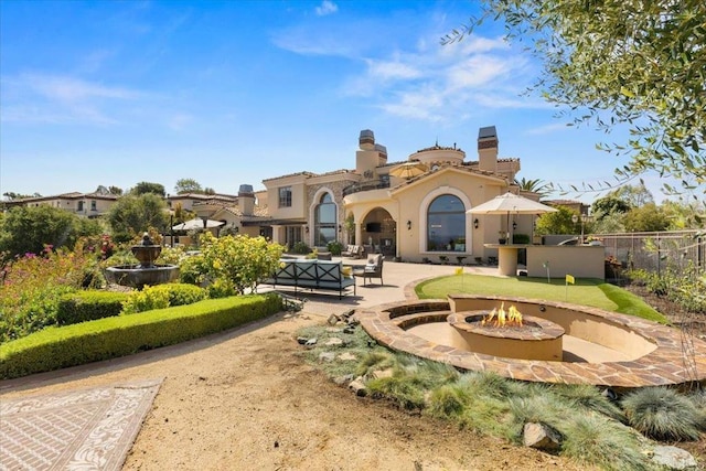 back of house with fence, an outdoor living space with a fire pit, stucco siding, and a patio area