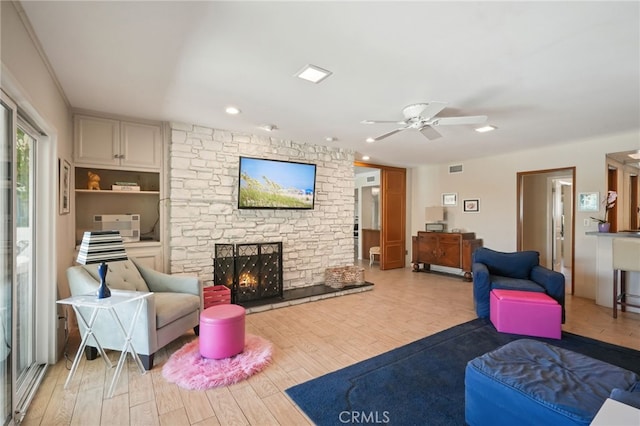 living area featuring recessed lighting, ceiling fan, light wood finished floors, and a stone fireplace