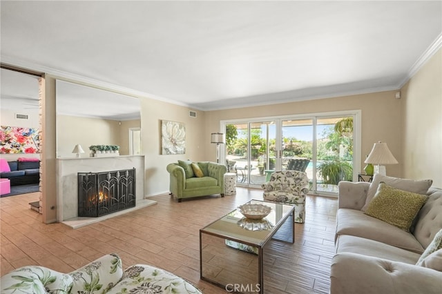 living area featuring ornamental molding, a lit fireplace, wood finished floors, and visible vents