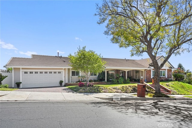 ranch-style home with an attached garage, stucco siding, driveway, and a tiled roof
