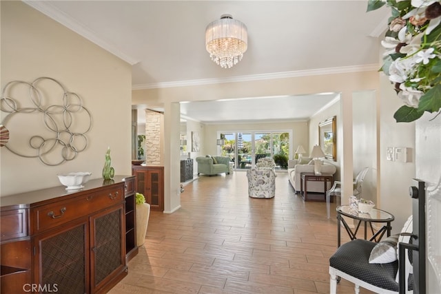 foyer with crown molding, baseboards, an inviting chandelier, and light wood-style flooring