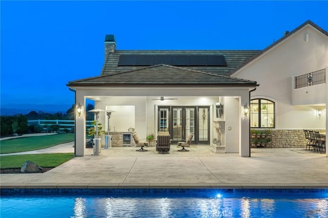 rear view of property with french doors, ceiling fan, stucco siding, and a patio area