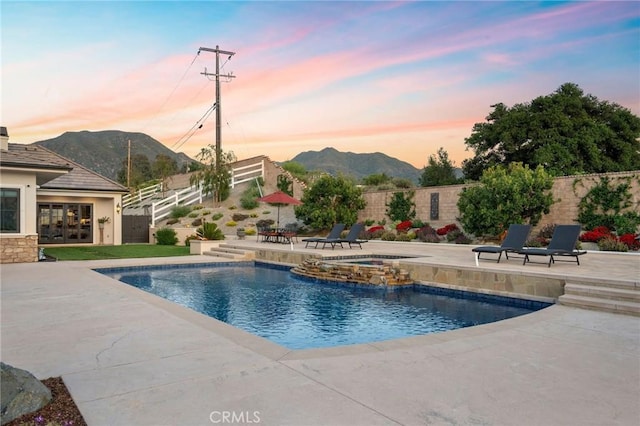 view of swimming pool with a mountain view, a fenced backyard, an in ground hot tub, and a patio area