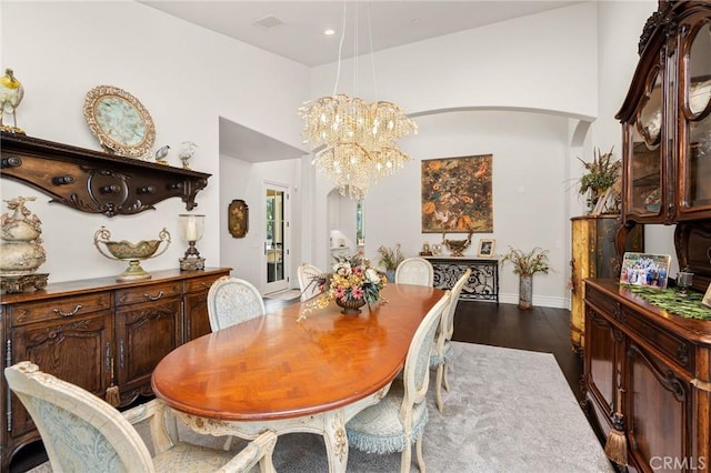 dining space with visible vents, dark wood-style floors, arched walkways, baseboards, and a notable chandelier