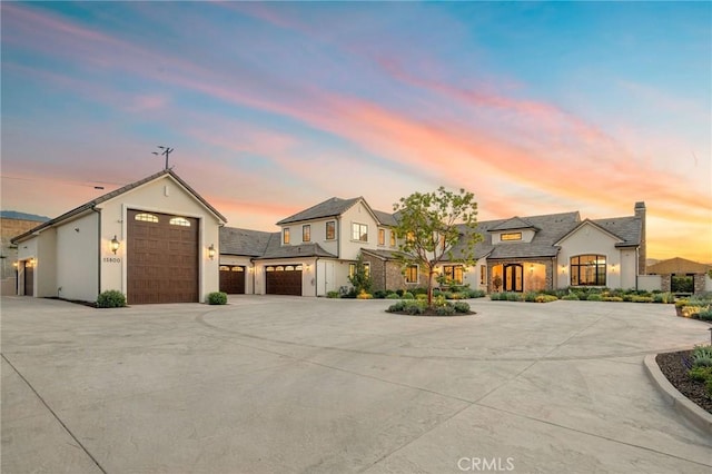 modern farmhouse with a chimney, stucco siding, and driveway