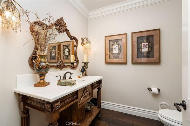 half bath featuring baseboards, toilet, ornamental molding, wood finished floors, and vanity
