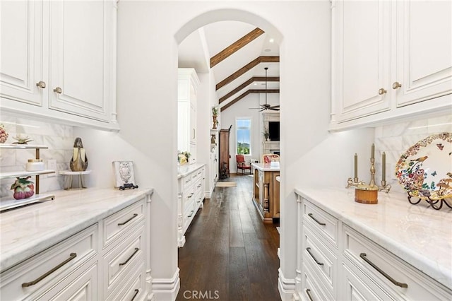 bar with tasteful backsplash, a ceiling fan, dark wood finished floors, and arched walkways