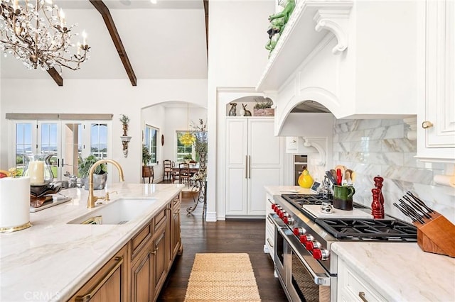 kitchen with a sink, an inviting chandelier, brown cabinetry, double oven range, and arched walkways