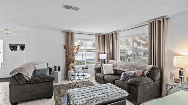 living room featuring light tile patterned floors, a textured ceiling, visible vents, and plenty of natural light