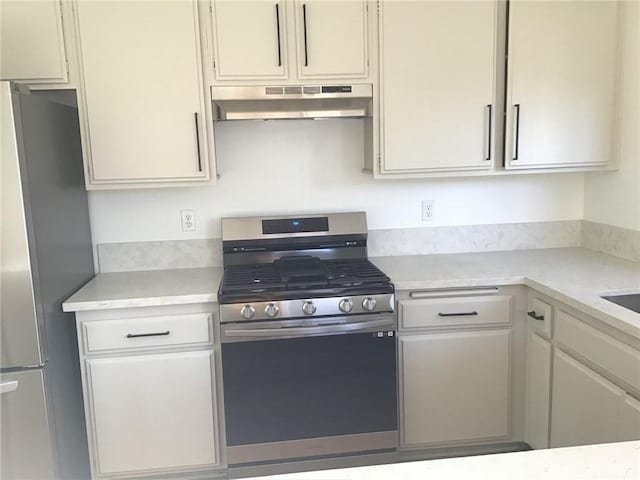 kitchen featuring stainless steel appliances, light countertops, and under cabinet range hood