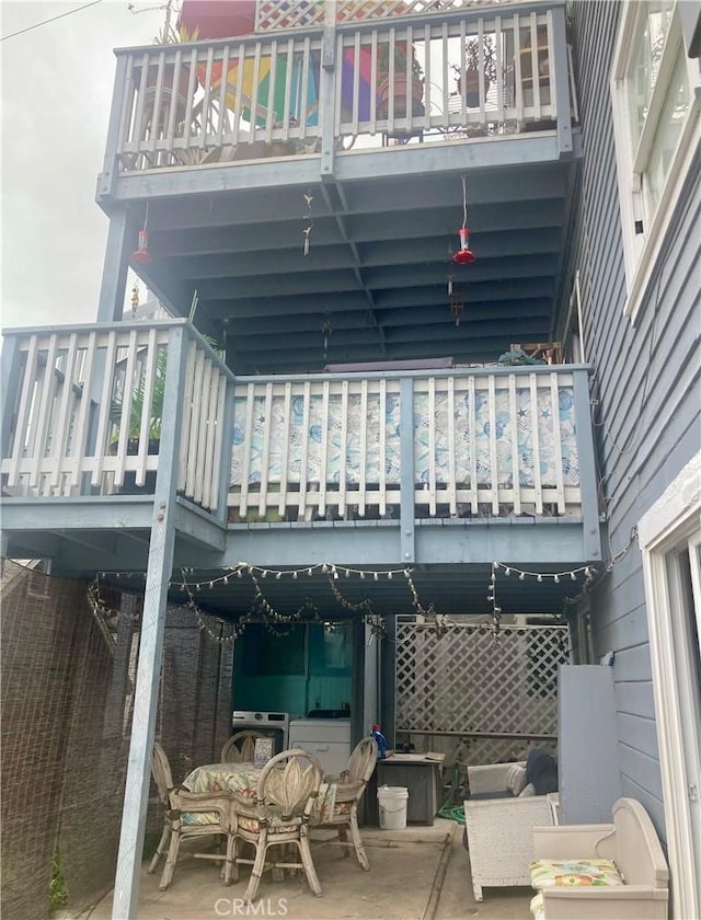 back of property with washer / clothes dryer, a balcony, and a patio area