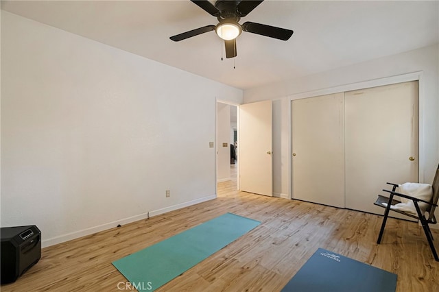 exercise area featuring light wood-style floors, ceiling fan, and baseboards