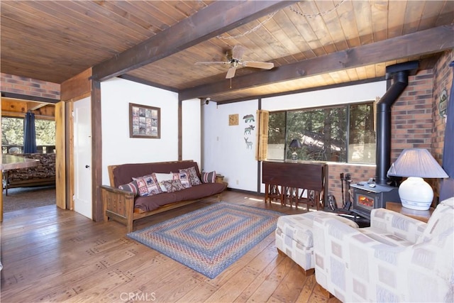 interior space with beamed ceiling, a wood stove, hardwood / wood-style floors, and wood ceiling