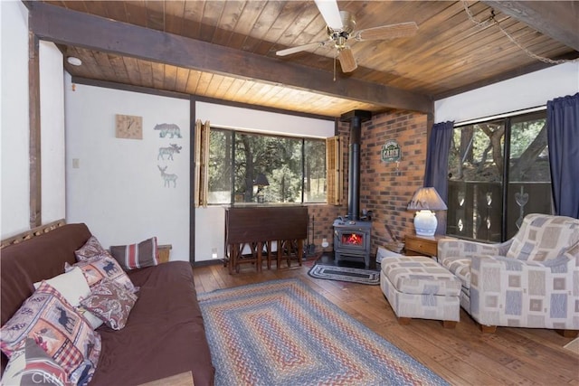 living room with wood-type flooring, a wood stove, wooden ceiling, and a wealth of natural light