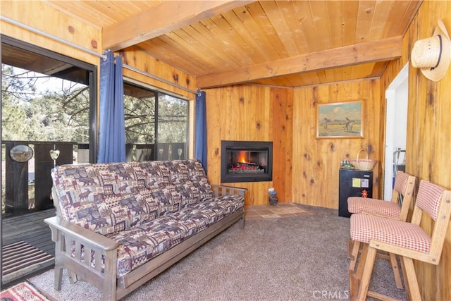 living room with wooden ceiling, beamed ceiling, wood walls, and carpet