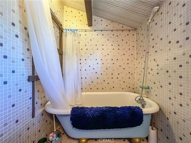 bathroom featuring lofted ceiling and tile walls