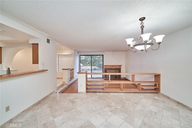 unfurnished dining area featuring an inviting chandelier, baseboards, a textured ceiling, and visible vents