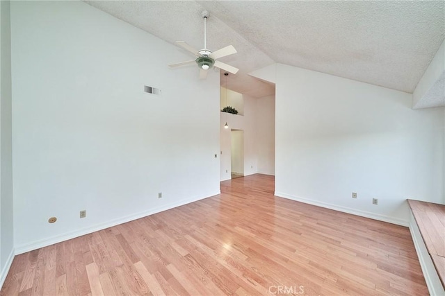spare room featuring ceiling fan, light wood finished floors, a textured ceiling, and lofted ceiling