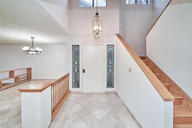 entrance foyer with baseboards, a high ceiling, stairs, and a chandelier
