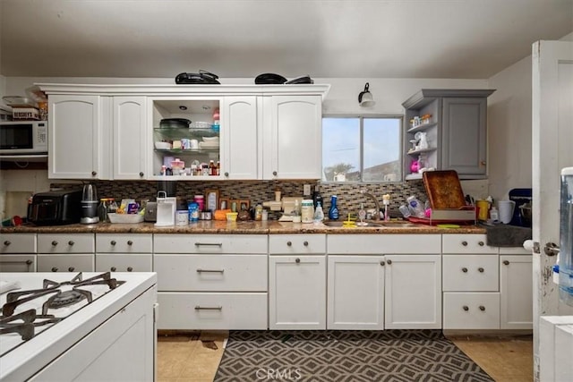 kitchen with white cabinetry, white appliances, open shelves, and a sink