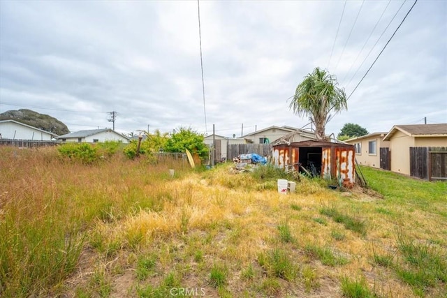 view of yard featuring fence, a shed, and an outbuilding