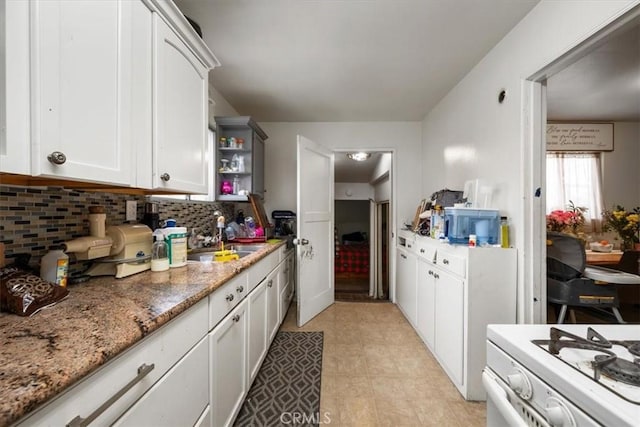 kitchen featuring white cabinetry, tasteful backsplash, open shelves, white gas range oven, and a sink