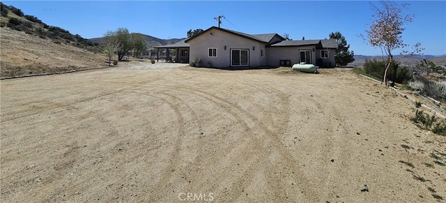 rear view of house with a mountain view and stucco siding