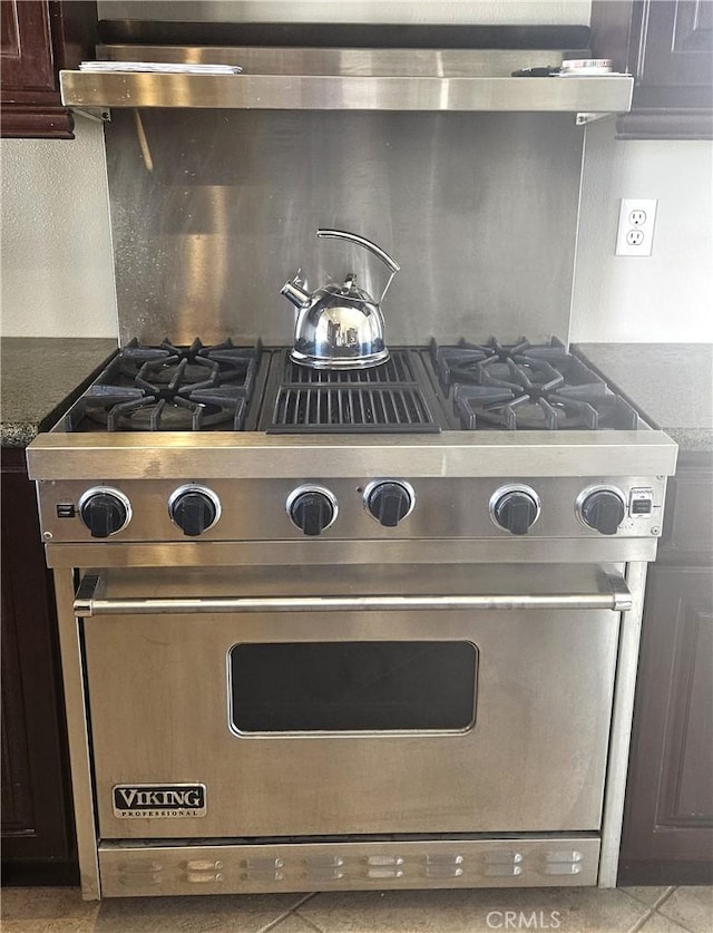 details featuring luxury range, backsplash, and dark brown cabinetry