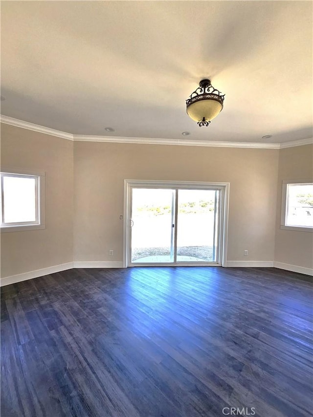 spare room with baseboards, ornamental molding, and dark wood finished floors
