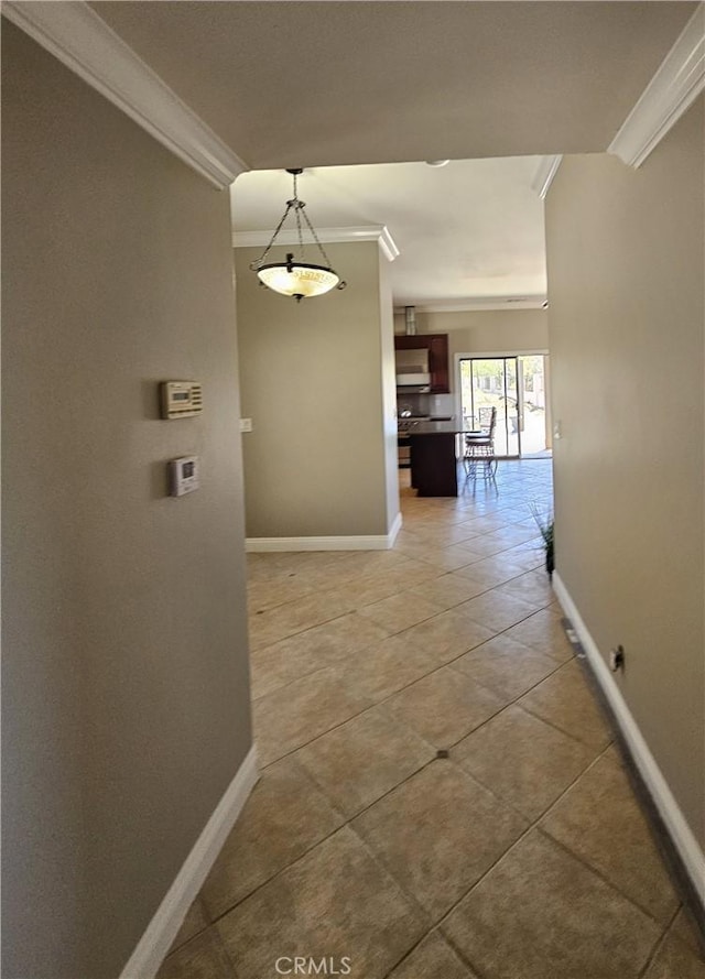 hallway featuring ornamental molding, light tile patterned flooring, and baseboards