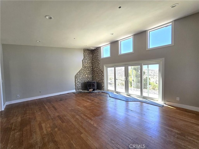 unfurnished living room featuring baseboards, recessed lighting, a high ceiling, and wood-type flooring