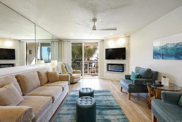 999 N Pacific St Unit E108, Oceanside, CA 92054 - living area featuring a fireplace, a textured ceiling, wood finished floors, and a ceiling fan