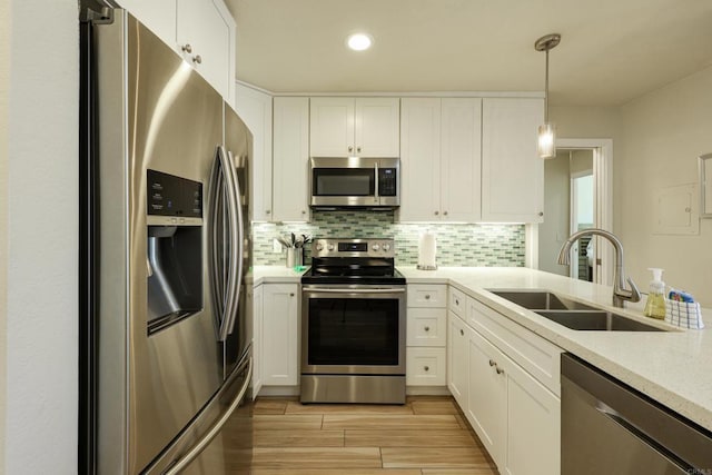 999 N Pacific St Unit E108, Oceanside, CA 92054 - kitchen featuring decorative backsplash, white cabinets, a sink, stainless steel appliances, and decorative light fixtures