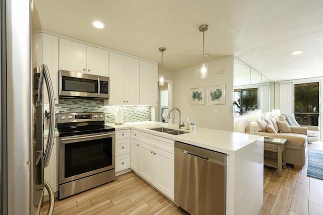 999 N Pacific St Unit E108, Oceanside, CA 92054 - kitchen with a sink, stainless steel appliances, a peninsula, white cabinets, and open floor plan