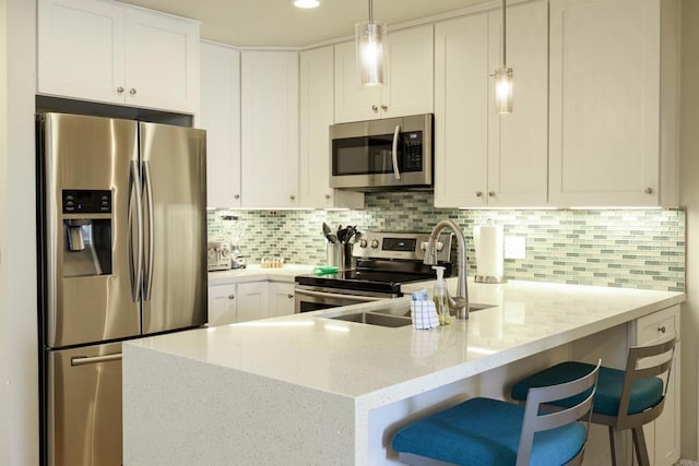 999 N Pacific St Unit E108, Oceanside, CA 92054 - kitchen with a sink, stainless steel appliances, a peninsula, light stone counters, and white cabinets