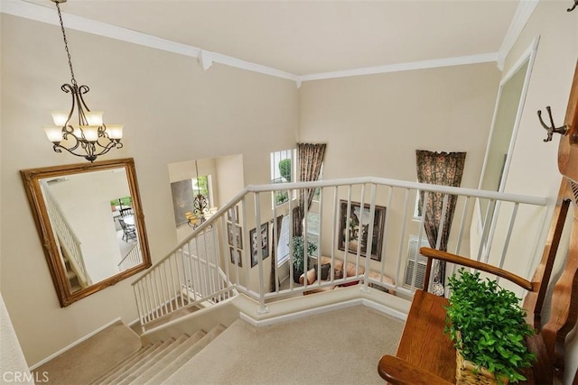 stairway with a chandelier, carpet floors, and crown molding