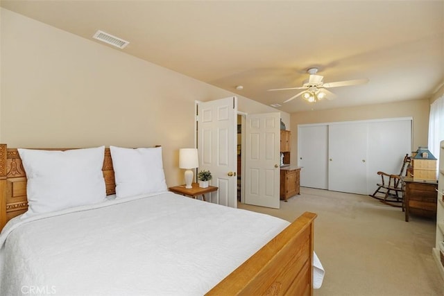 bedroom featuring a closet, visible vents, a ceiling fan, and light carpet