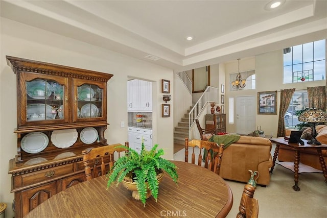 carpeted dining room with a chandelier, stairway, a tray ceiling, and recessed lighting
