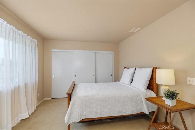 bedroom featuring baseboards, visible vents, light carpet, and a closet
