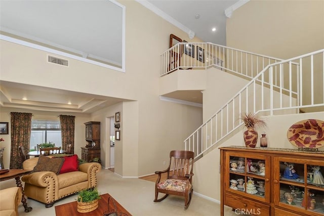 carpeted living area featuring baseboards, visible vents, ornamental molding, and stairway