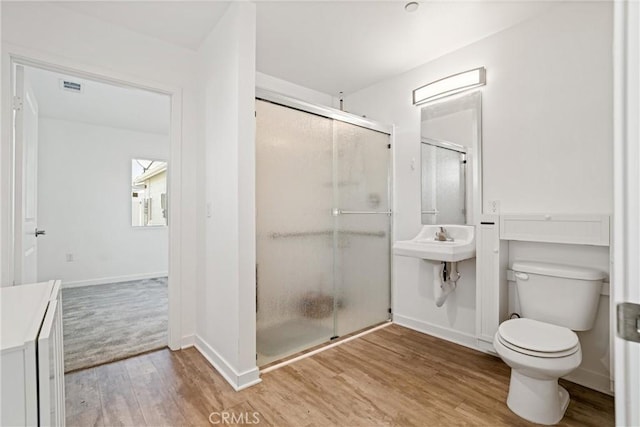 full bathroom with wood finished floors, a shower stall, toilet, baseboards, and visible vents